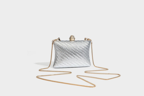 Small structured rectangular metallic woven-texture clutch bag with jeweled knob clasp and gold-tone chain strap, detail view