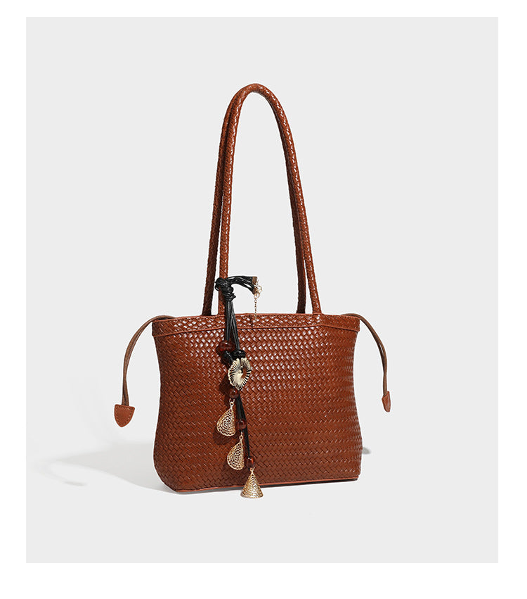 Structured woven leather-look tote bag in dark brown with long shoulder straps, side drawstring ties, and gold filigree