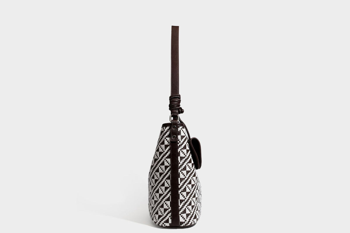 Geflochtene Schultertasche mit geometrischem Ethno-Muster, Besatz in dunkelbrauner Lederoptik, langem verstellbarem Träger und kleinem hängendem Reißverschluss