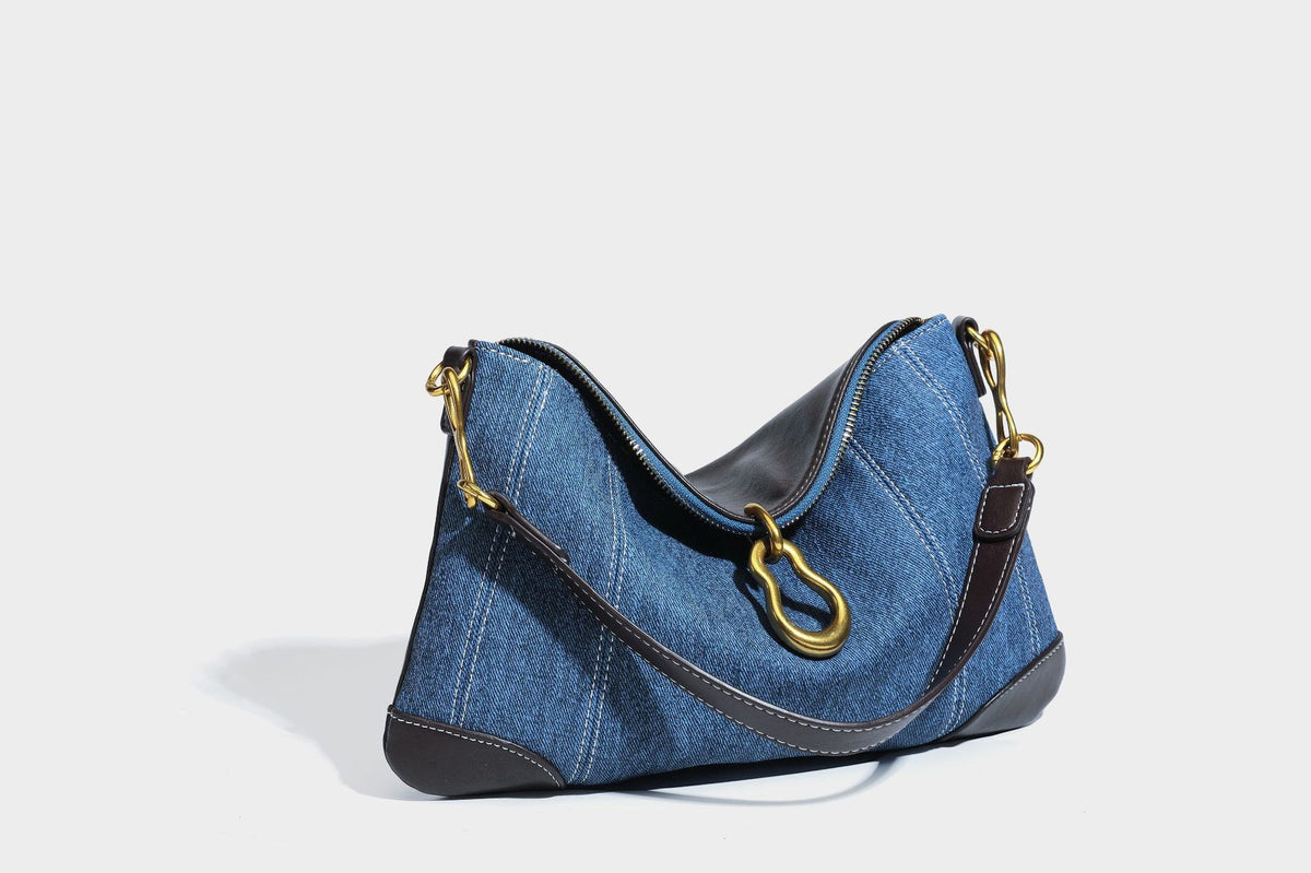 Slouchy denim shoulder bag with dark leather-look trim, gold-tone chain-link hardware, and top zipper closure, detail view 32