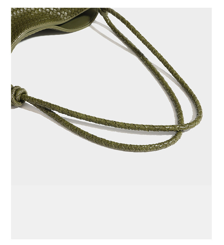 Olive green woven leather-look bucket bag with braided crossbody strap, knotted adjustment, and gold-tone tassel charm with