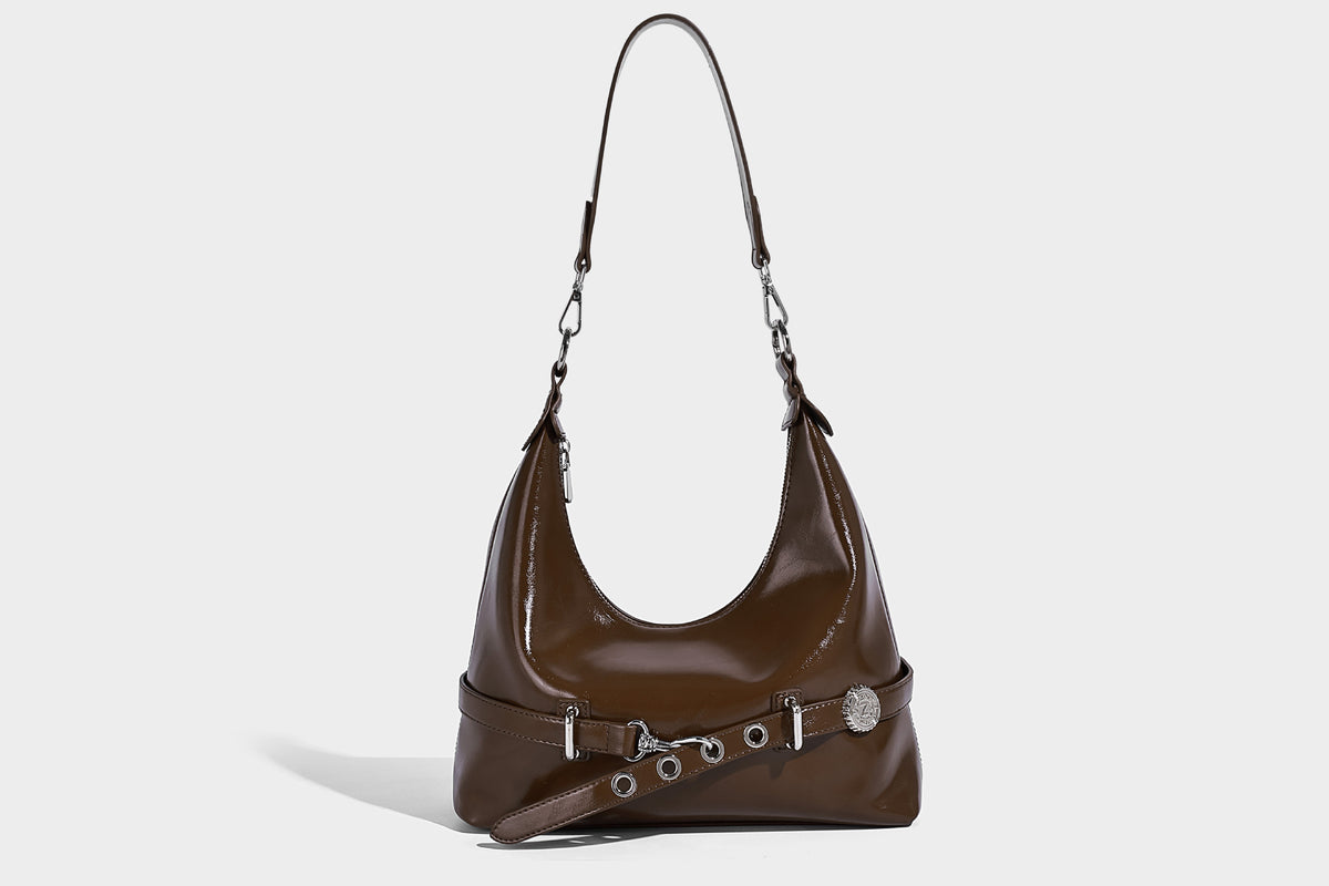 Glossy black slouchy hobo shoulder bag with silver-tone hardware, belt-style grommet strap at base, and long adjustable