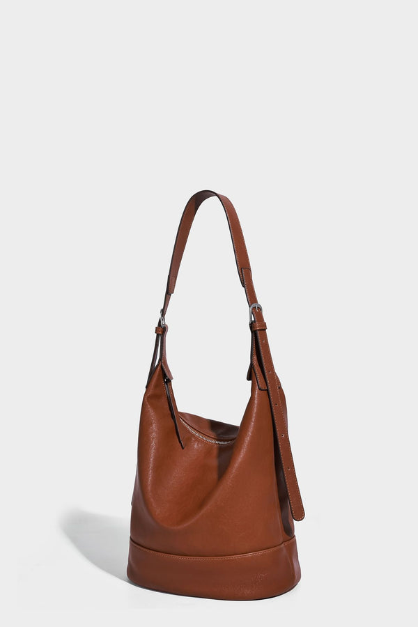 Slouchy bucket hobo shoulder bag in dark brown with glossy leather-look finish, top zip closure, and long adjustable, detail