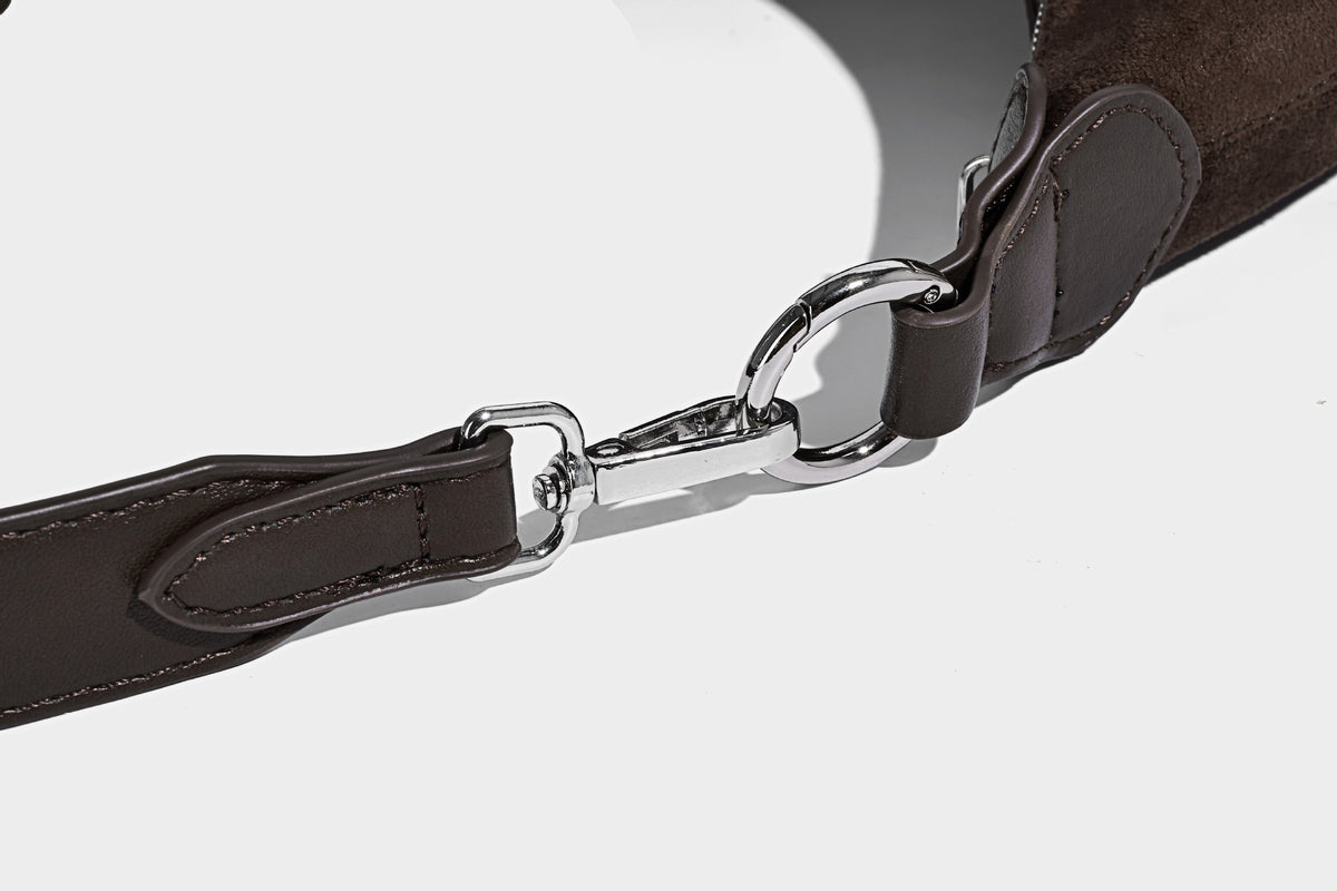 Hobo-Schultertasche in Dunkelbraun mit velourslederartiger Oberfläche, silberfarbener Gürtelschnalle und Ösenbeschlägen, verstellbarem Riemen, Detailansicht