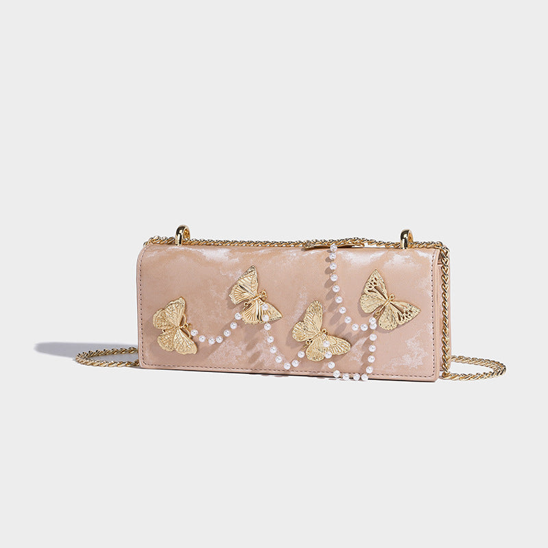 Structured rectangular flap crossbody bag with gold butterfly charms and pearl strand embellishment on a gold-tone chain