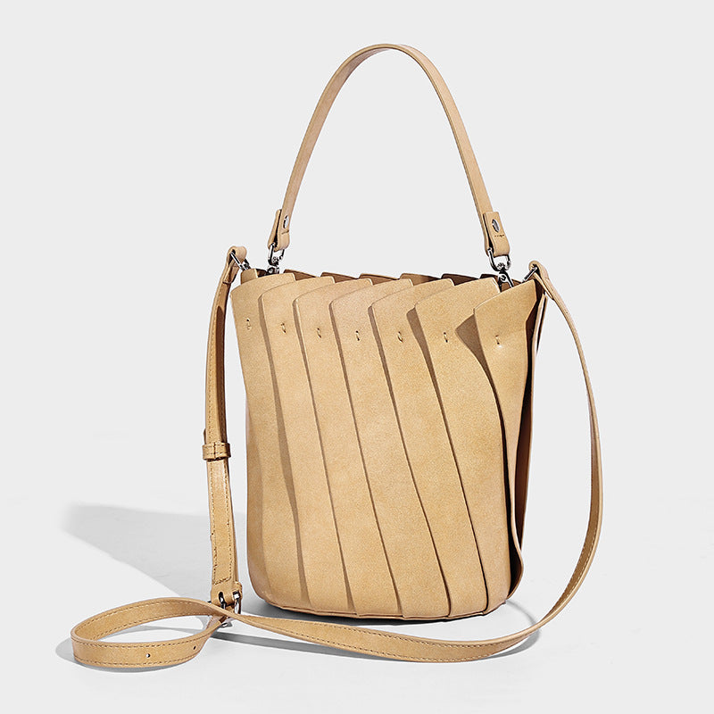 Structured pleated-panel bucket bag with curved top handle and detachable adjustable shoulder strap in smooth matte, detail