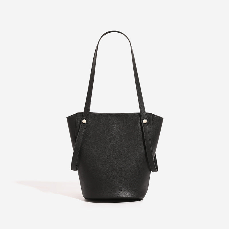 Strukturierte schwarze Bucket-Tote-Bag in Lederoptik mit schmalen Schulterriemen, Nietenbeschlägen in Silberoptik und sich verjüngendem Korpus, Vorderansicht