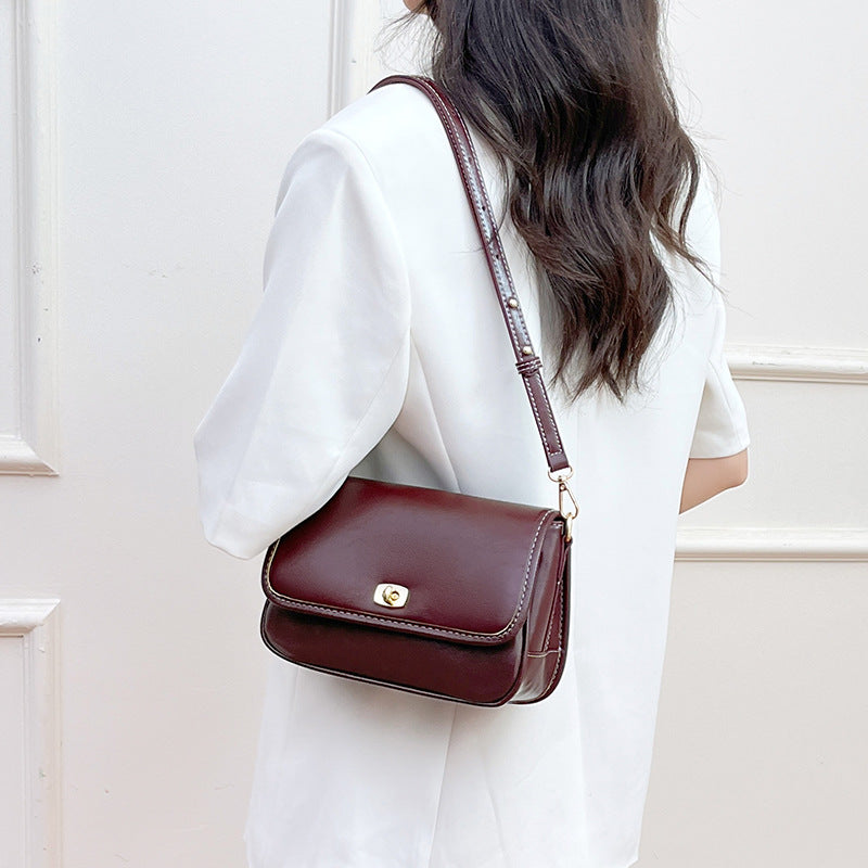 Small structured flap crossbody bag in glossy leather-look finish with gold-tone turn-lock closure and adjustable strap