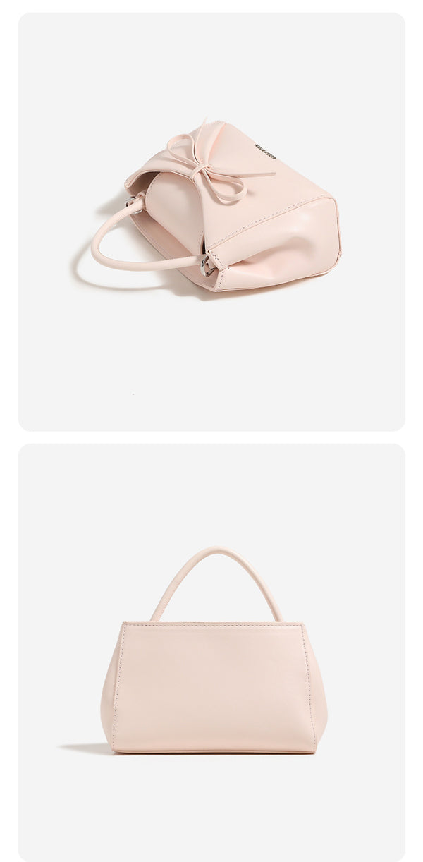Structured mini trapezoid top-handle crossbody bag with sculpted bow front detail, smooth matte finish, silver-tone hardware