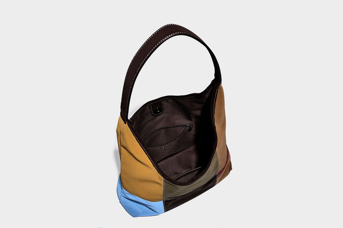 Multicolor patchwork hobo shoulder bag with brown tan olive mustard red and blue suede-look panels, contrast white stitching