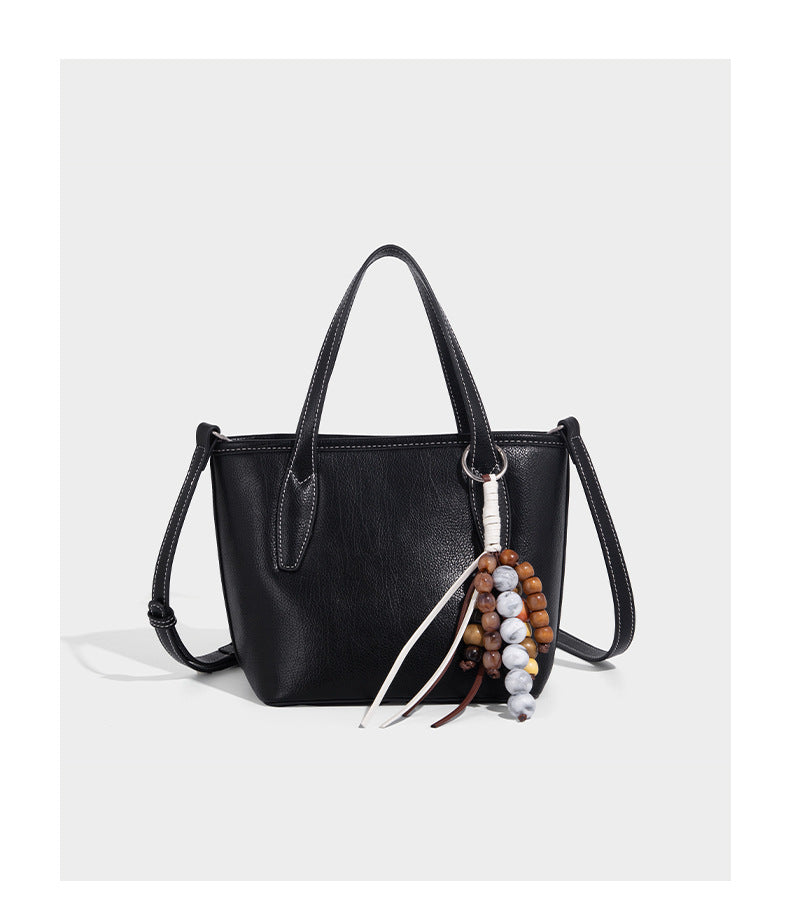 Compact structured bucket tote bag with pebbled textured finish, dual top handles, silver-tone lock hardware, and detachable