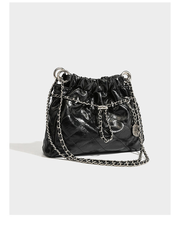 Glossy diamond-quilted drawstring bucket bag with silver chain shoulder strap and medallion charm, detail view 8