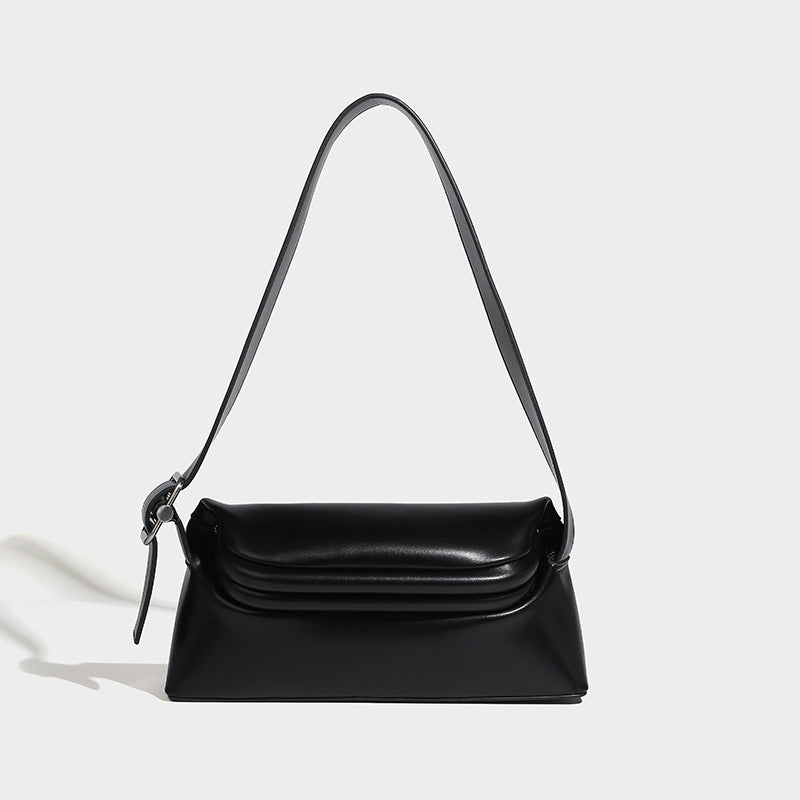 Compact structured baguette shoulder bag with smooth leather-look finish, zip top, and adjustable silver-buckle strap, detail