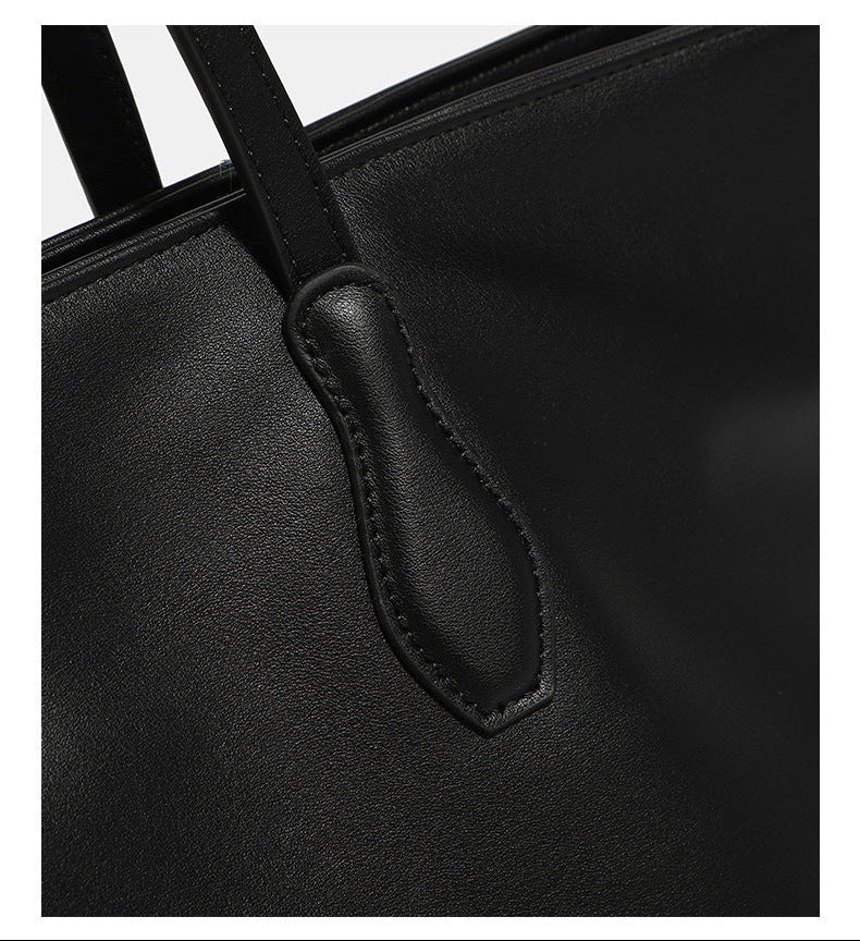 Large black leather-look trapezoid tote bag with double shoulder straps and purple accent hardware, detail view 9