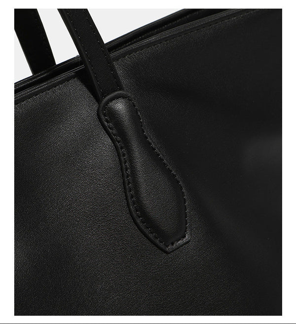 Large black leather-look trapezoid tote bag with double shoulder straps and purple accent hardware, detail view 9