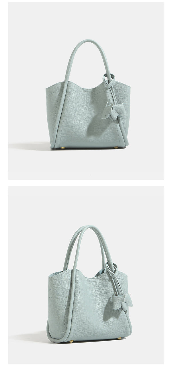Small structured pebbled leather-look bucket tote bag with bow charm tie closure and gold-tone hardware, detail view 9