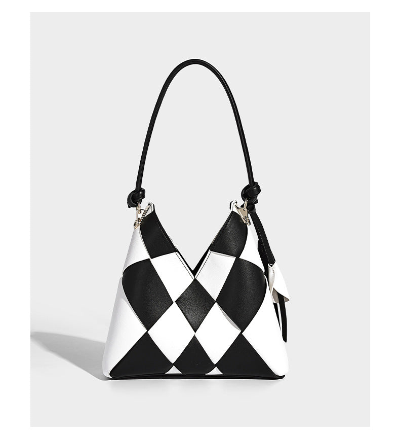 Compact bucket shoulder bag with black-and-white diamond patchwork panels, knotted top handle, gold-tone hardware, and