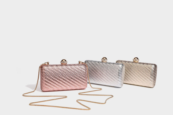 Small structured metallic woven-texture box clutch bag with jeweled kiss-lock dome clasp and slim gold chain strap, detail