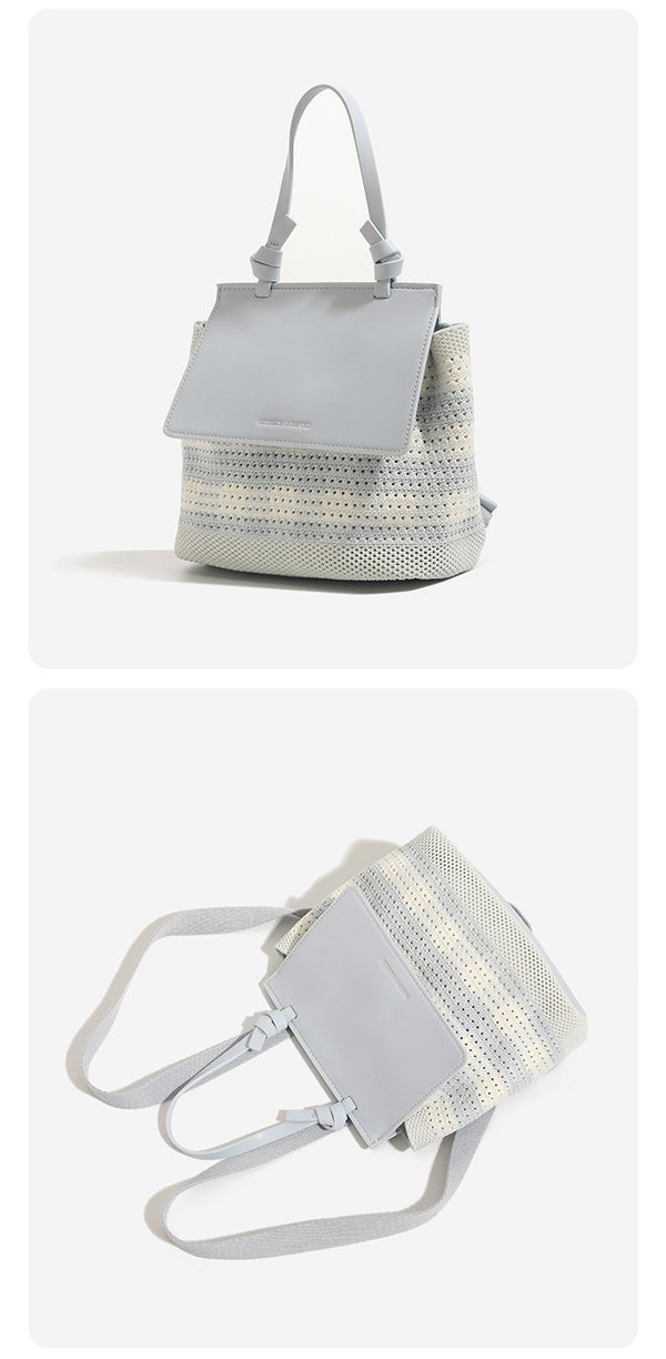 Small structured woven-body flap bag with smooth leather-look front panel, knotted top handle, and wide adjustable shoulder