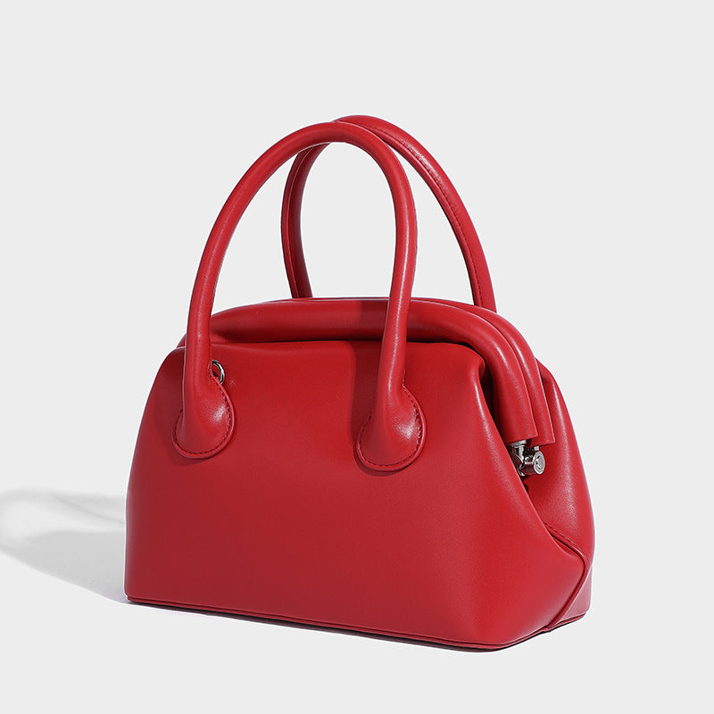 Small structured shell top-handle bag in red with heart charm and braided cord detail, smooth leather-look finish, detail