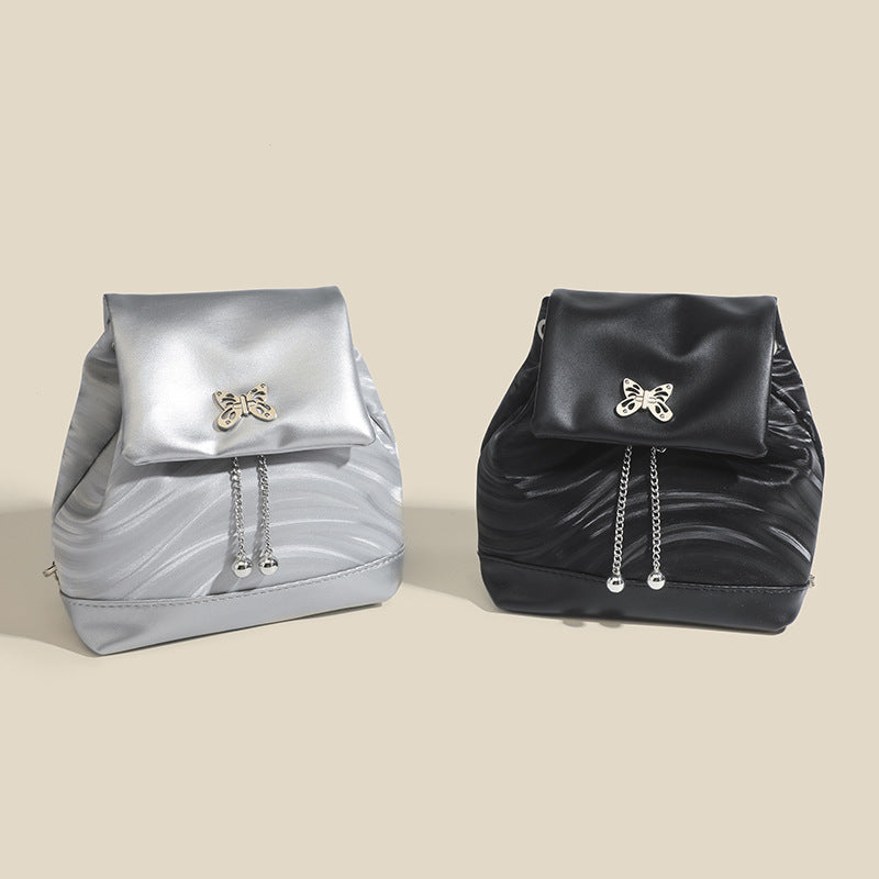 Kompakter Rucksack in Handtaschenform aus wellenförmig geprägter Lederoptik mit silberfarbenem Schmetterlingsverschluss und Kettenriemen, Detailansicht 2
