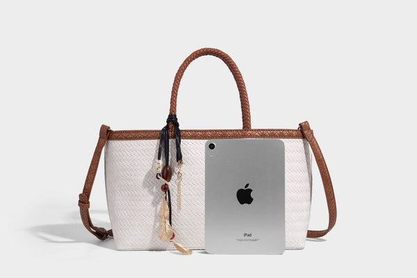 Structured woven-texture tote bag with brown braided top handles, decorative tassel charm, and detachable shoulder strap