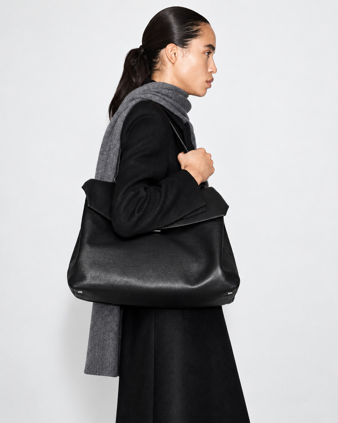Large black slouchy leather-look shoulder bag with V-shaped envelope flap, silver-tone clasp, and adjustable strap, detail