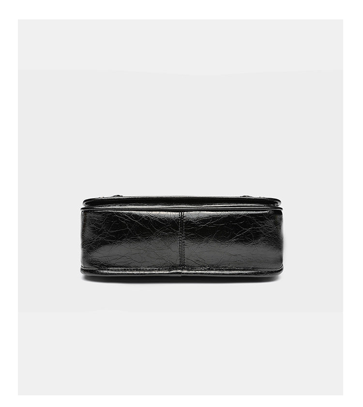 Small structured rectangular crossbody bag with crinkle leather-look finish, front zip pocket, gunmetal stud hardware, and