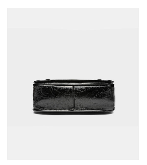 Small structured rectangular crossbody bag with crinkle leather-look finish, front zip pocket, gunmetal stud hardware, and