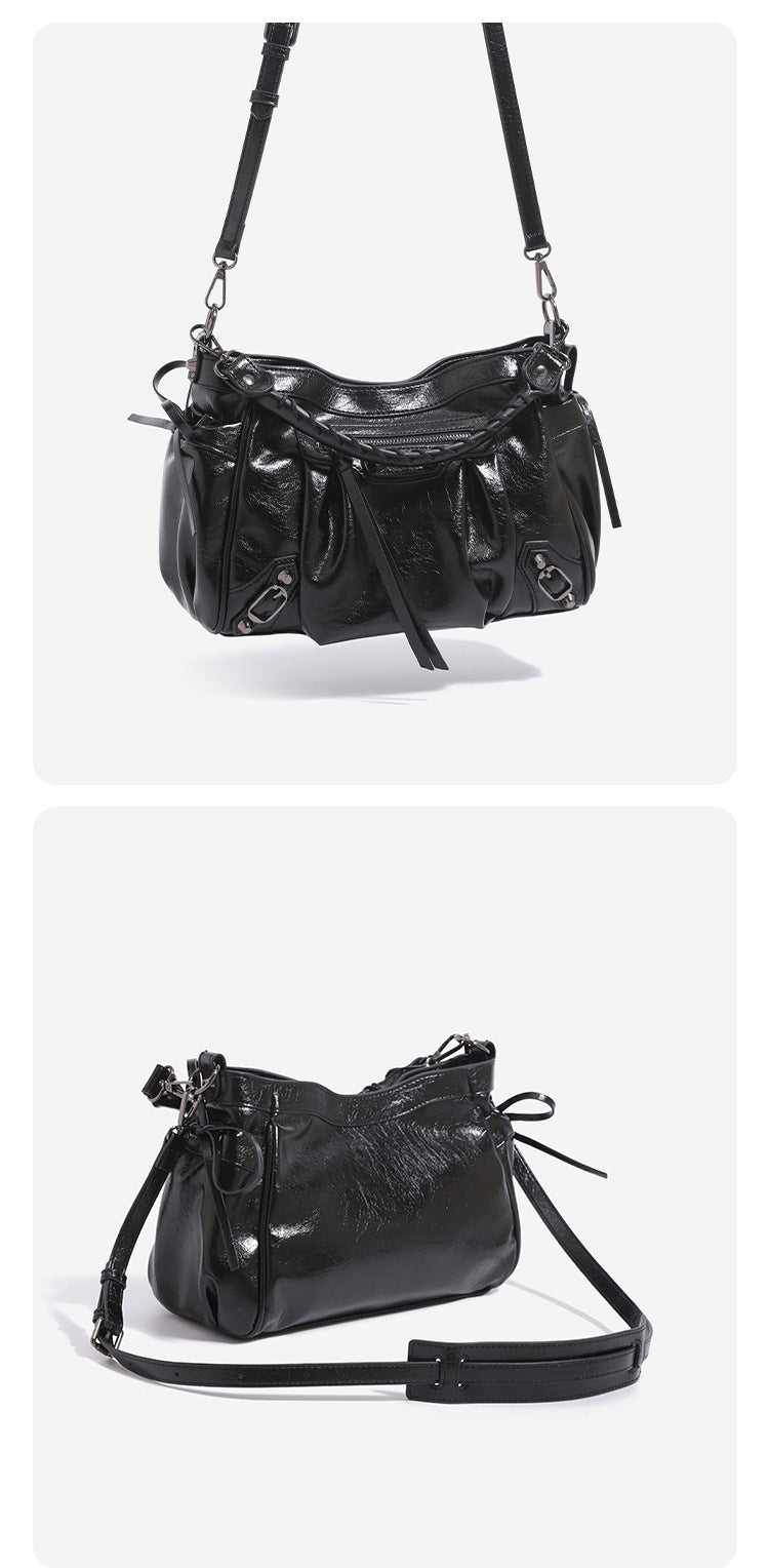 Glossy ruched leather-look shoulder bag with silver stud hardware, fringe trim, front zip pocket, and top handle, detail view