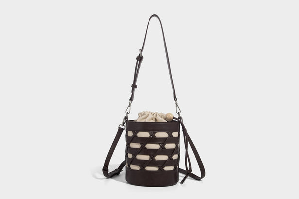 Small cylindrical woven lattice bucket bag with leather-look black trim, beige canvas body, wooden bead drawstring closure