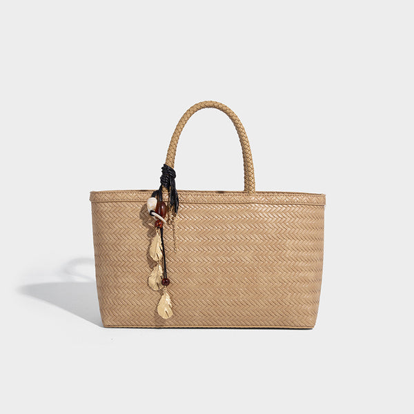 Structured woven-texture tote bag with brown braided top handles, decorative tassel charm, and detachable shoulder strap