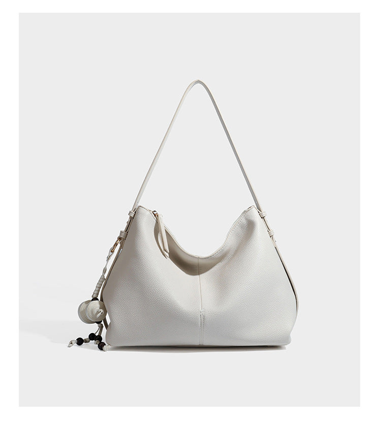 Slouchy hobo shoulder bag with pebbled leather-look finish, zip-top closure, gold-tone hardware, and hanging bead charm