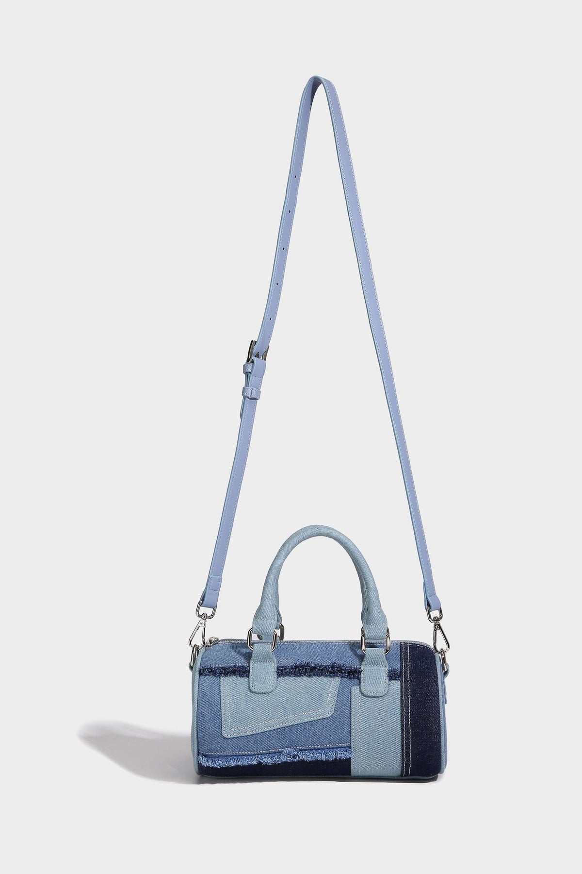 Mini barrel handbag in light and dark denim patchwork with frayed seam trim, dual top handles, top zip closure, and, detail