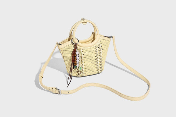 Kleine strukturierte Beuteltasche aus geflochtenem Material mit rundem Tragegriff in Lederoptik, silberfarbenen Beschlägen und perlenbesetztem Quastenanhänger, Detail