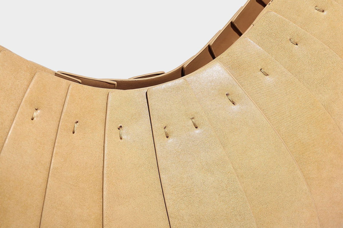 Crescent half-moon shoulder bag with vertical panel seaming, matte-satin leather-look finish, and adjustable gold-tone