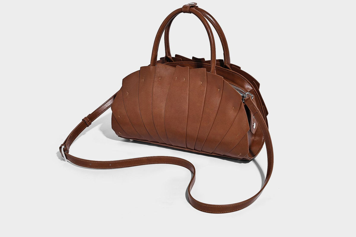 Structured dome satchel with fan-pleated leather-look exterior, dual top handles, and detachable shoulder strap, detail view