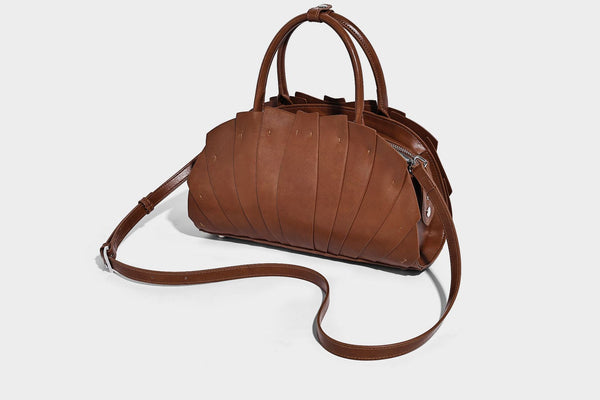 Structured dome satchel with fan-pleated leather-look exterior, dual top handles, and detachable shoulder strap, detail view