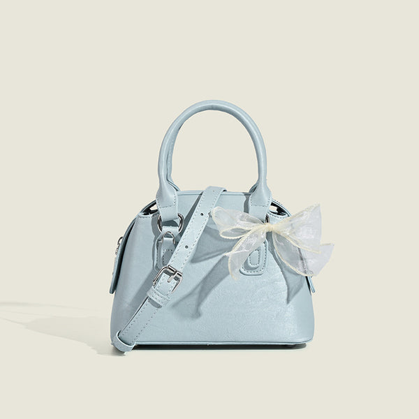 Small structured Boston bag in cream with glossy crinkled finish, sheer bow accent, silver-tone hardware, dual top handles