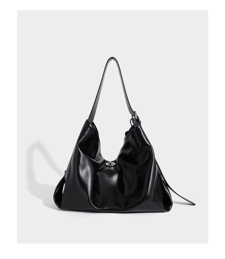 Große schwarze, weich fallende Hobo-Schultertasche in glänzender Lederoptik mit mit Ösen besetztem Riemen, silberfarbenen Metallbeschlägen und abnehmbarem