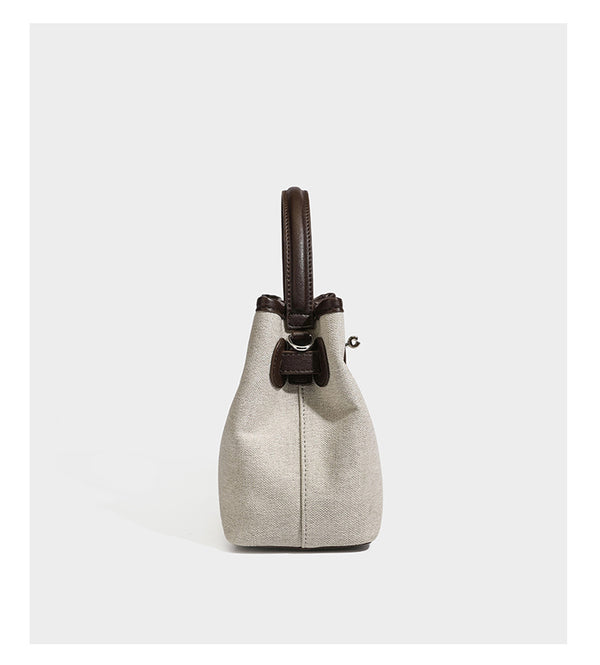 Small structured beige canvas top-handle bag with dark brown leather-look trim, silver turn-lock hardware, and detachable