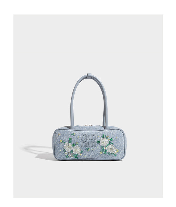 Small structured light blue denim-texture bowling bag with white floral bead embroidery, dual rounded top handles, and