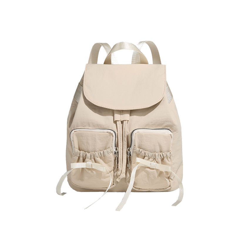 Soft matte nylon drawstring backpack with ruched bow-detail front zip pockets, top carry handle, and silver-tone hardware