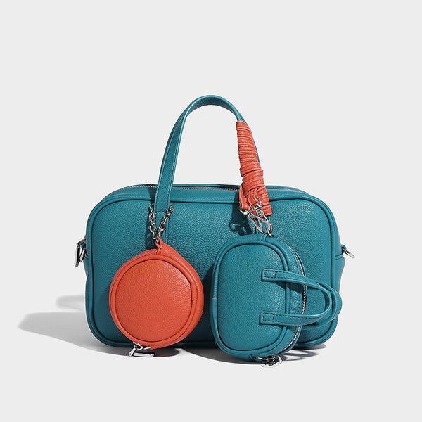 Structured pebbled leather-look Boston bowling bag in tan with blue detachable round mini pouch, dual top handles, and