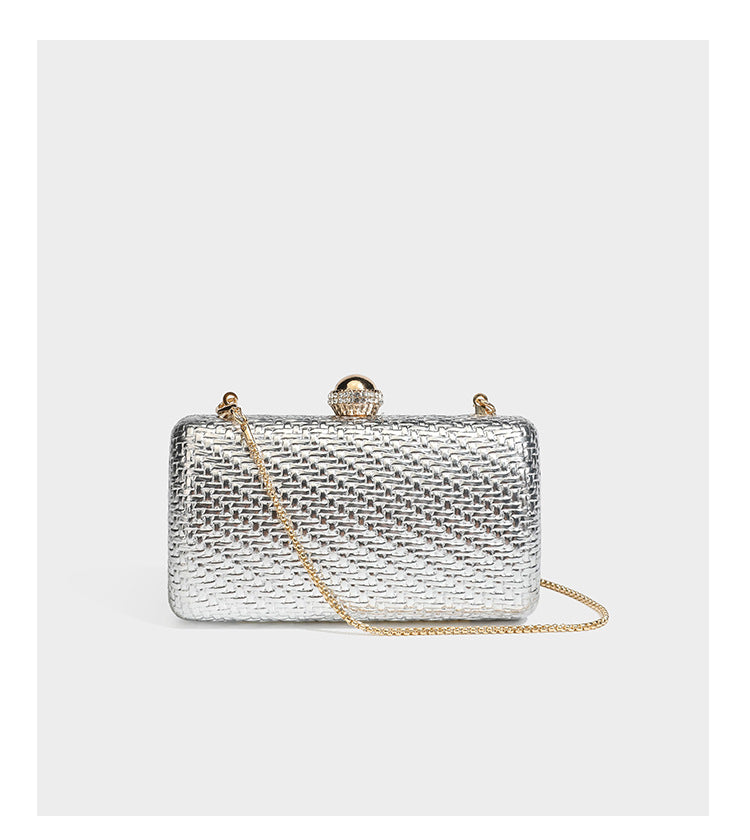 Small structured metallic woven-texture box clutch bag with jeweled kiss-lock dome clasp and slim gold chain strap, detail