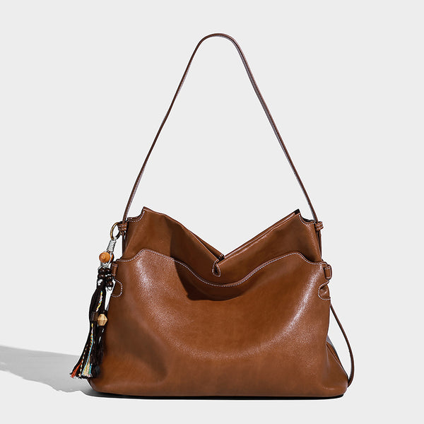 Large slouchy leather-look hobo tote bag with open top, adjustable shoulder strap, and colorful tassel bead charm, detail