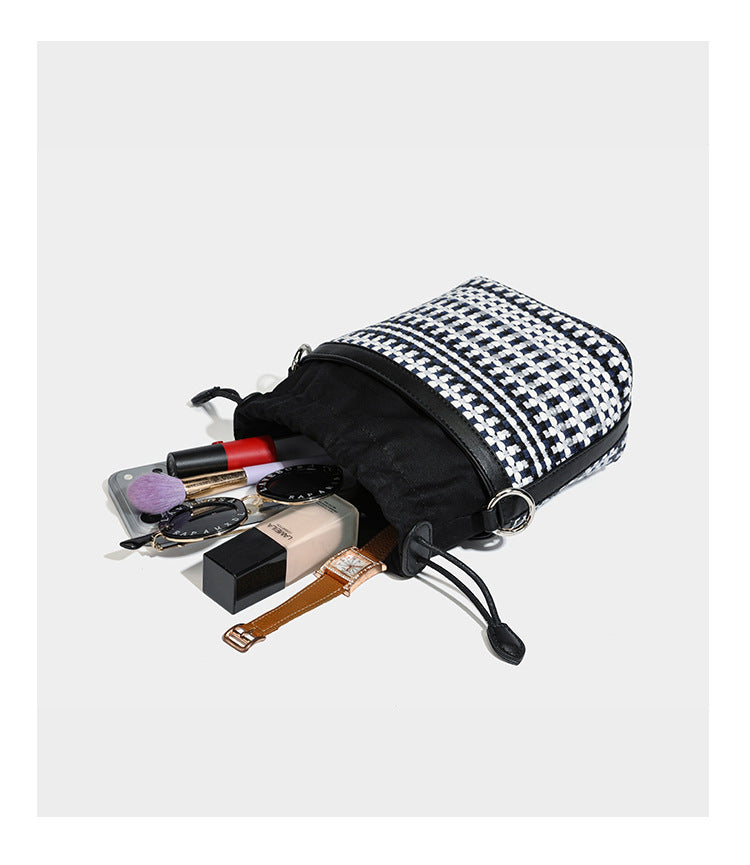 Small structured woven checker bucket bag with braided top handle, drawstring closure, and silver-tone hardware in black