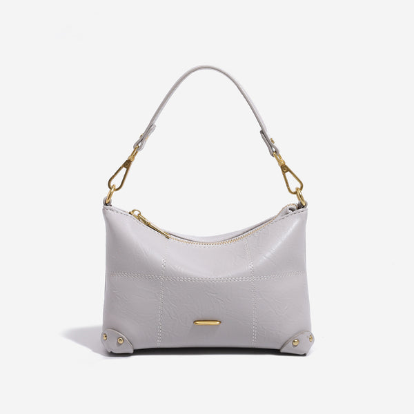 Small soft-structured shoulder bag with curved zip closure, stitched panel detailing, and gold-tone hardware, front view