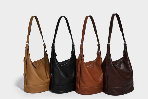 Slouchy bucket hobo shoulder bag in dark brown with glossy leather-look finish, top zip closure, and long adjustable, detail
