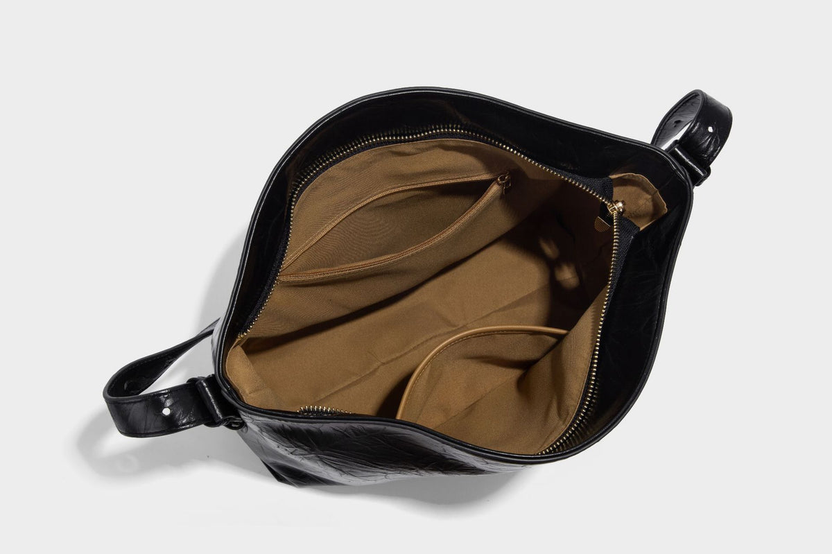 Large slouchy hobo shoulder bag in glossy crinkle leather-look finish with gold-tone emblem hardware and adjustable strap